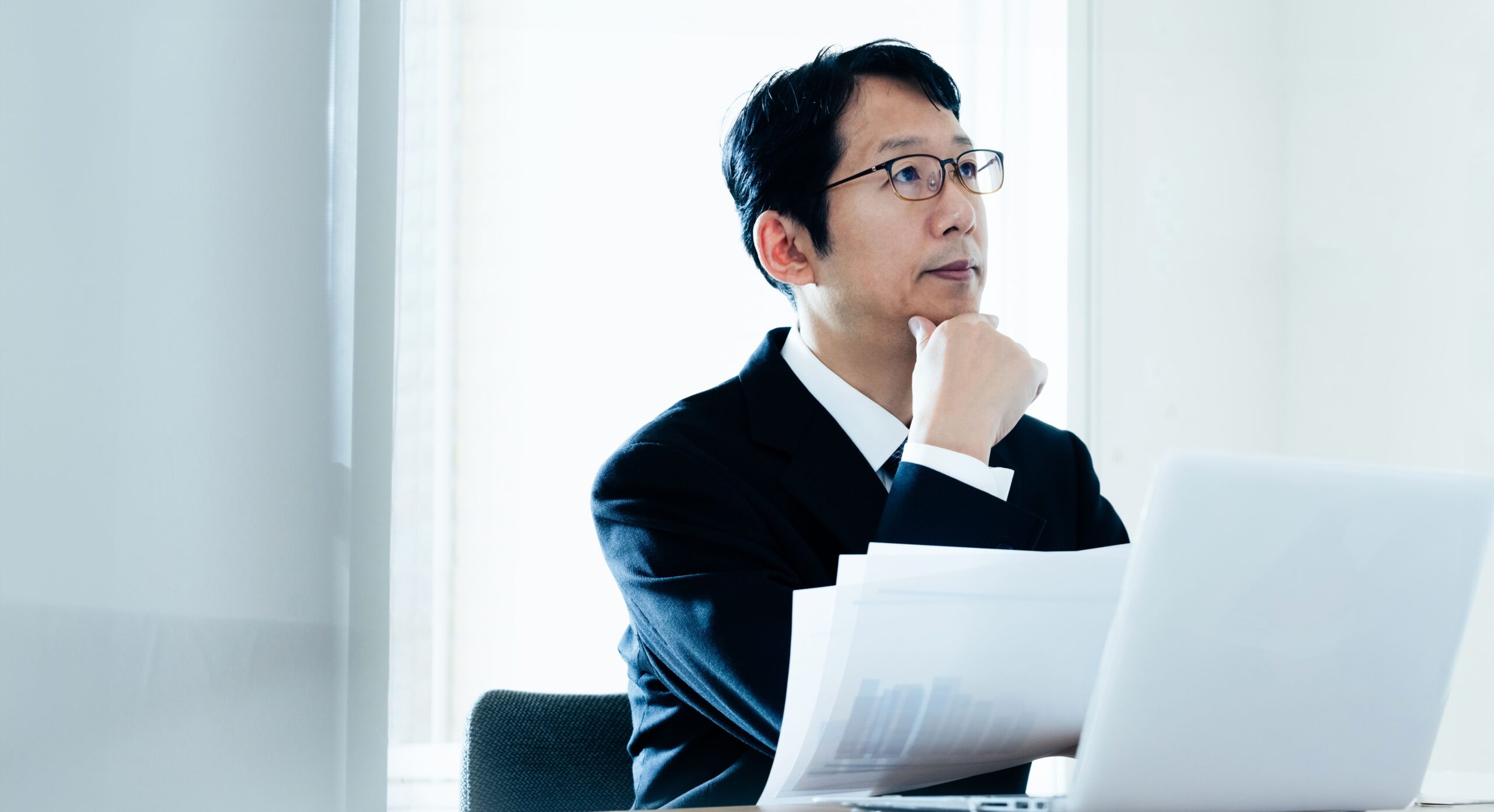 業績資料を前に役員報酬の決め方を考える経営者