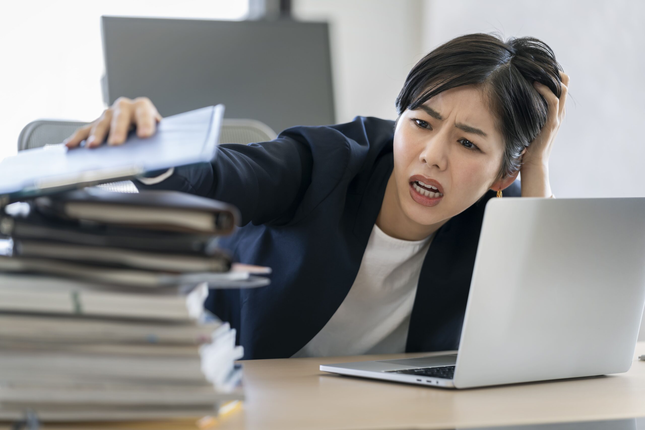 仕分けされていない領収書と請求書が積み上がり会計処理が滞っている経理の現場